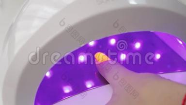 紫外线灯胶抛光指甲工艺在美容院。 沙龙手术。 主人给顾客`指甲涂上一层